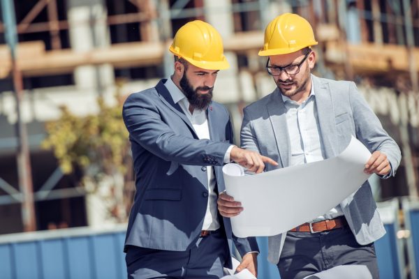 Two engineer have consulting meeting at construction site.Two construction worker working at construction site.